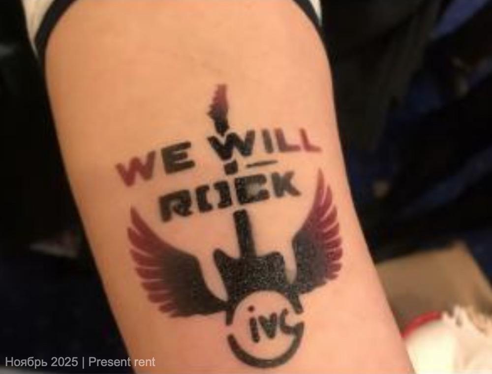 Временная татуировка на руке с надписью 'WE WILL ROCK' и изображением гитары и крыльев.