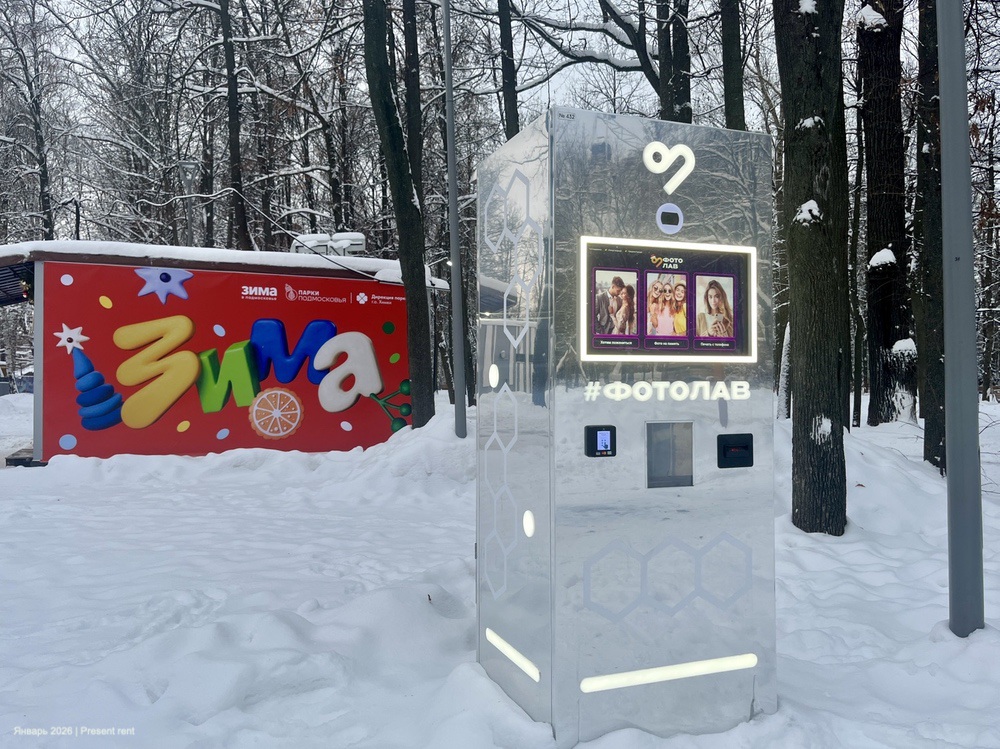 Современный фотобудка '#ФОТОЛАБ' на фоне зимнего пейзажа с елочными украшениями и снегом.