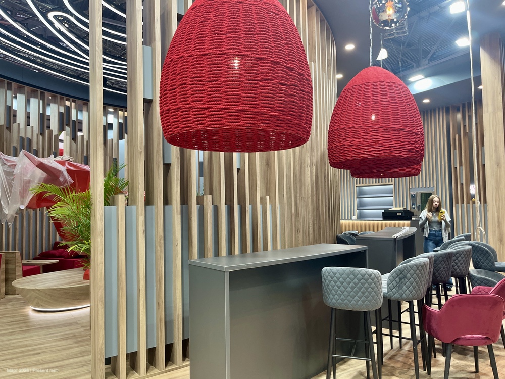 Современный интерьер с красными висячими светильниками, барной стойкой и стульями, оформленный в теплых деревянных тонах.