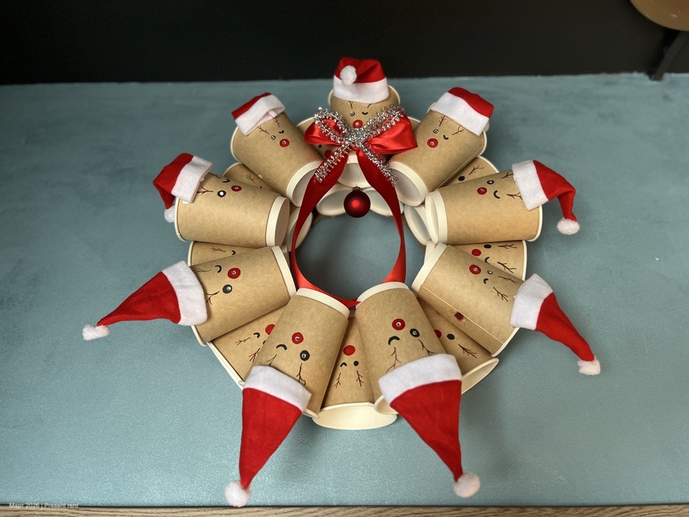 Рождественский венок из картонных трубочек с нарисованными лицами и санта-шапочками.
