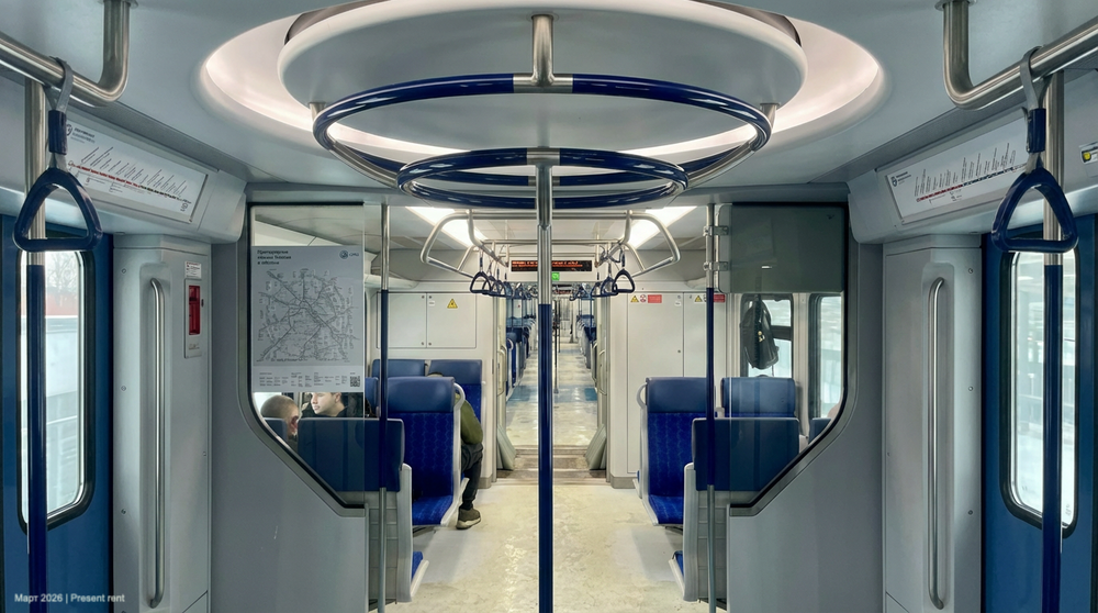 Интерьер современного поезда метро с сиденьями, поручнями и картой маршрута на стене.